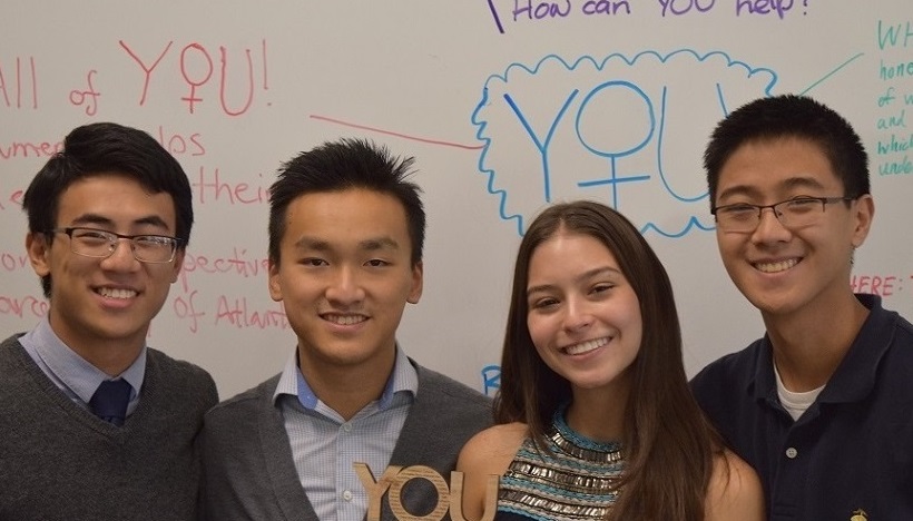 Four people standing together in front of a whiteboard