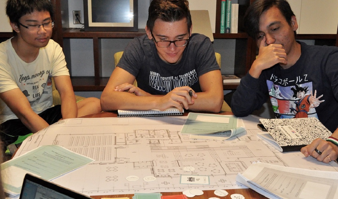 Three men staring at building plans